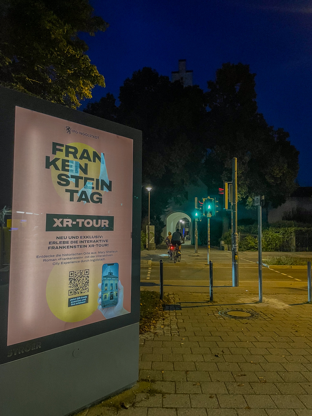 Ströer Werbeträger an einer Straße bei Nacht mit Plakat von einer Schnitzeljagd 